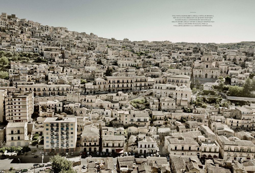 A sepia-toned panoramic cityscape view of historic buildings and architecture densely packed on hillsides.