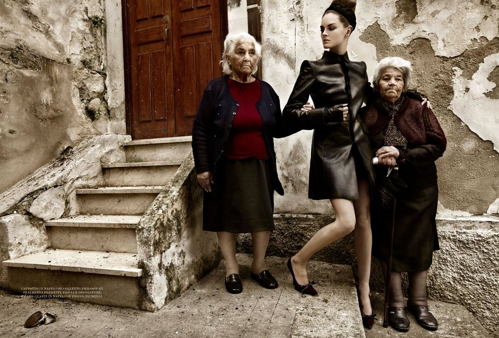 Three people pose on old stone steps against a weathered wall, wearing contrasting traditional and modern fashion styles.