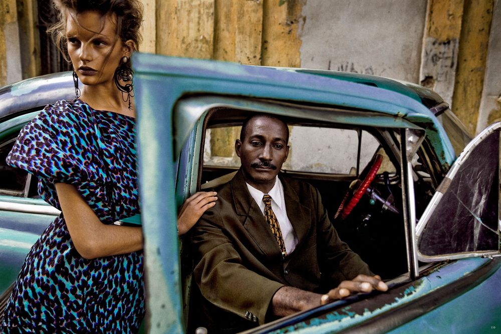 Vintage car scene with people in 1950s style clothing against wooden backdrop in vibrant colors.