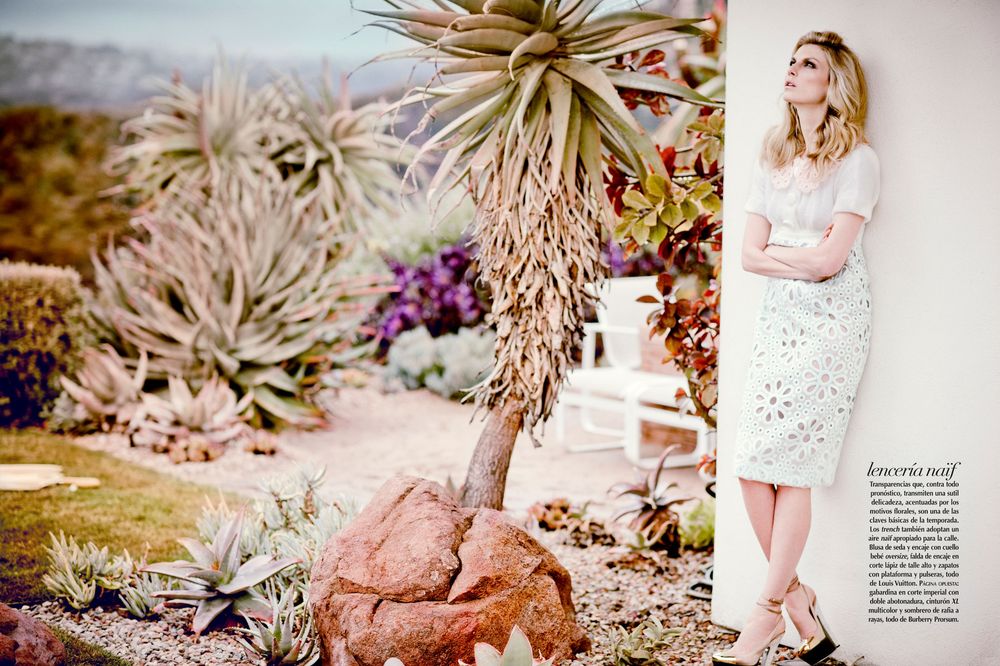 Fashion editorial photo in desert garden setting with white lace dress and succulent plants in soft natural lighting.