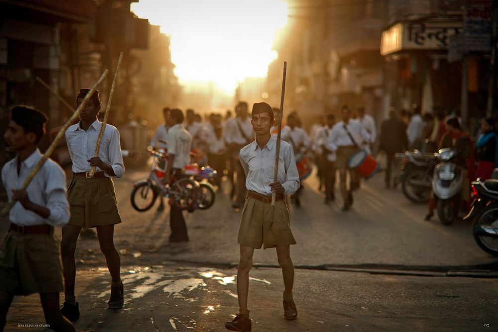 A busy street scene in Vietnam at sunset with motorbikes, pedestrians and golden sunlight filtering through the urban landscape.