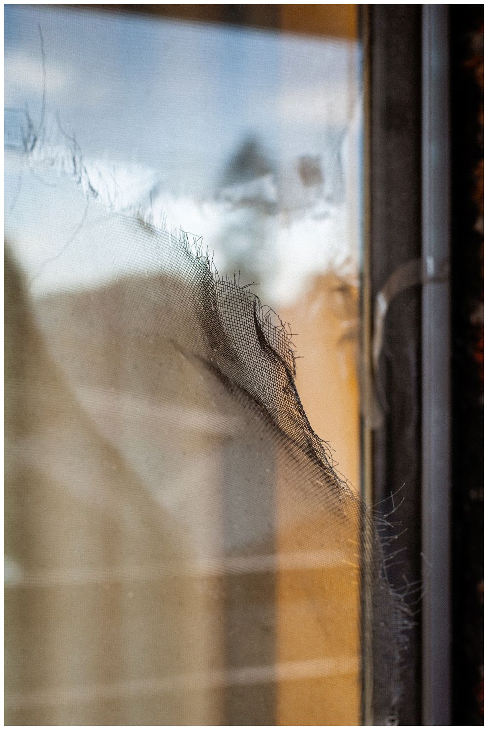 Close-up view of a window frame with condensation and frost patterns on the glass, creating an abstract textured appearance.
