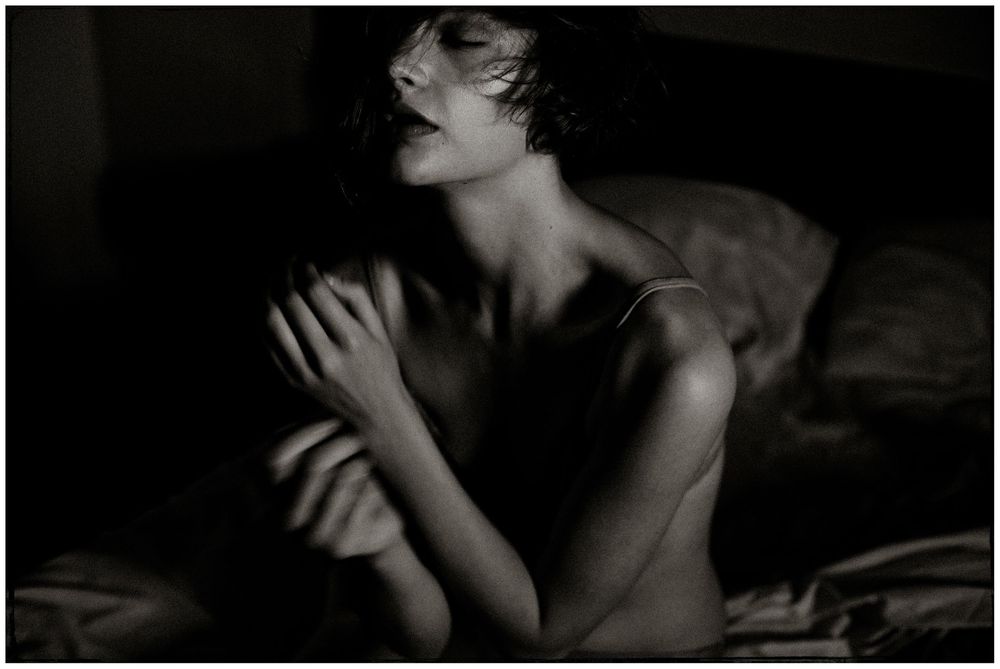 Black and white artistic portrait of a woman in contemplative pose with dramatic lighting and shadow effects.