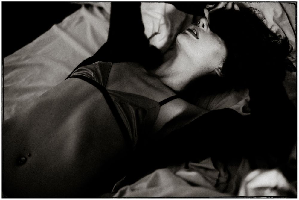 Black and white artistic photograph of a person reclining in dramatic lighting with shadows.