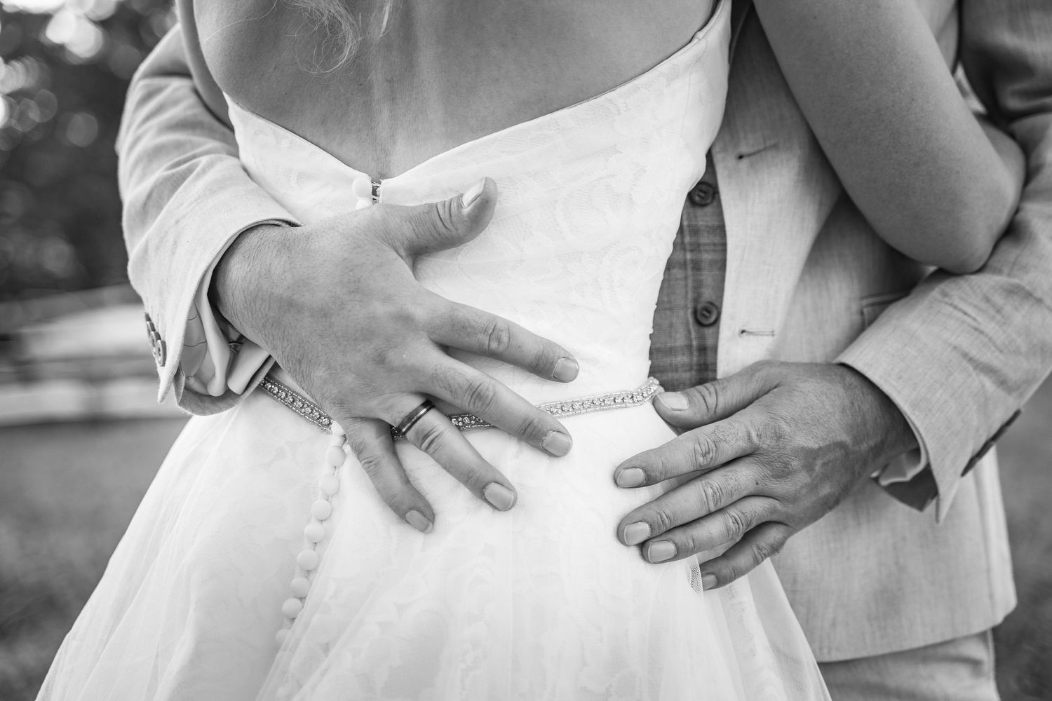 Detailaufnahme: Hände des Bräutigams auf dem Rücken der Braut – intime Momentaufnahme einer Hochzeit.
