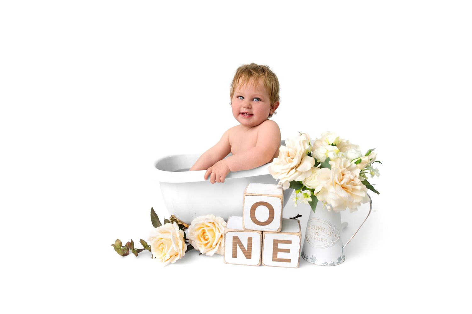 Happy baby splashes and plays in a white bathtub with a yellow rubber duck toy.