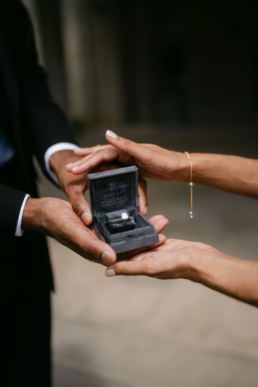 Close-up of hands presenting an engagement ring box during a romantic proposal moment.
