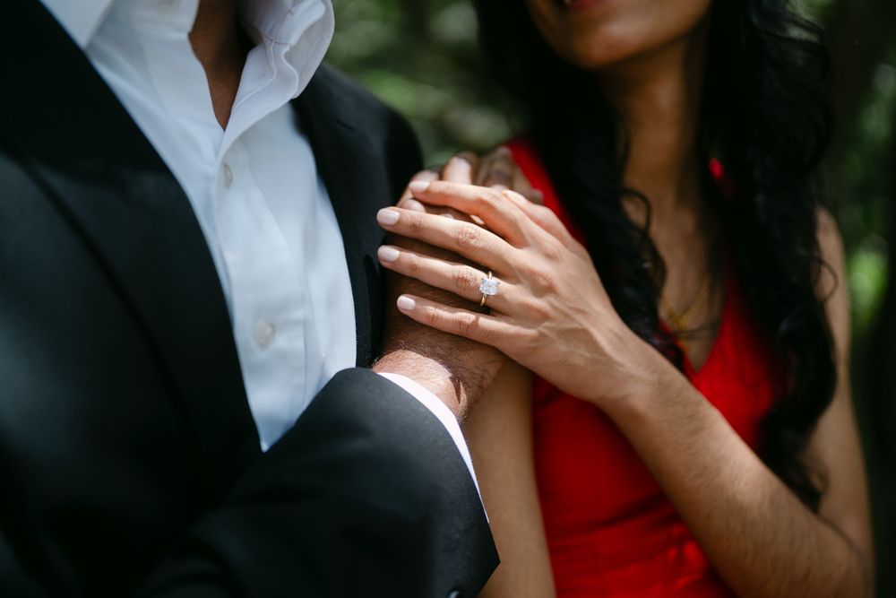 Close-up shot of two people dancing together, with hands clasped, wearing formal black and red attire.