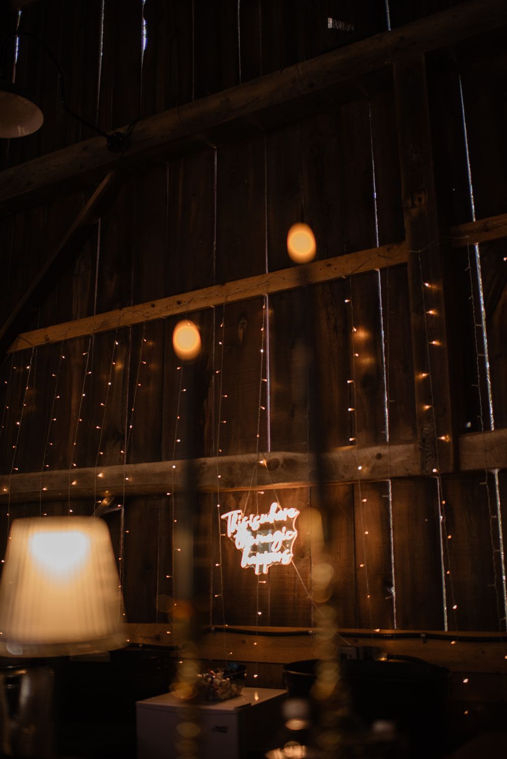 Dimly lit rustic interior with hanging string lights creating a warm, cozy ambiance against dark wooden beams.
