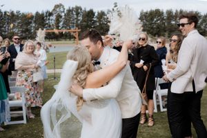 Wedding couple celebrates with guests outdoors as confetti fills the air.