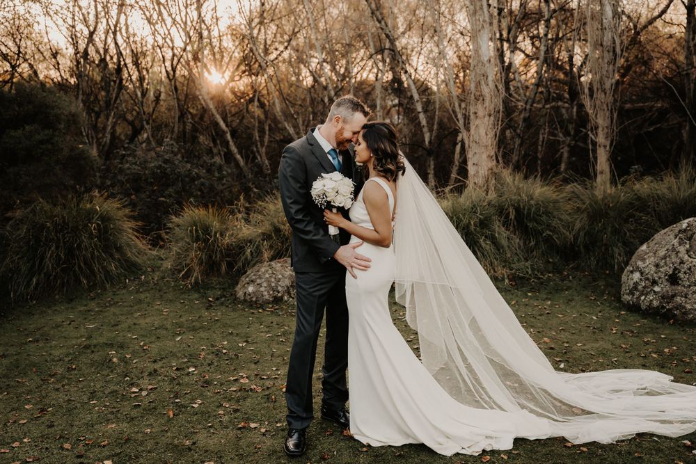 Wedding couple shares intimate moment at sunset in wooded natural setting.