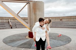 Playful wedding couple shares lighthearted moment on modern rooftop setting.