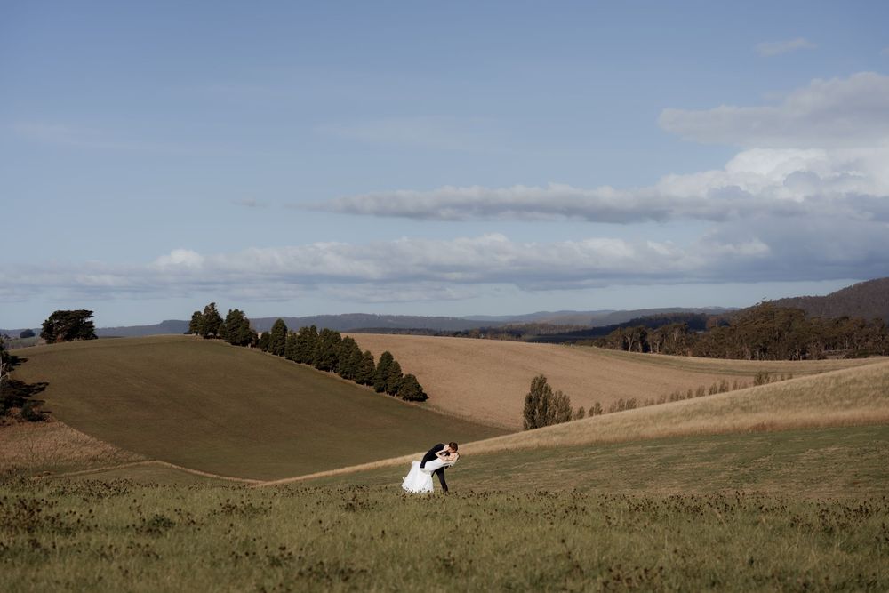 Rolling hills and grasslands stretch across a vast landscape under partly cloudy skies.