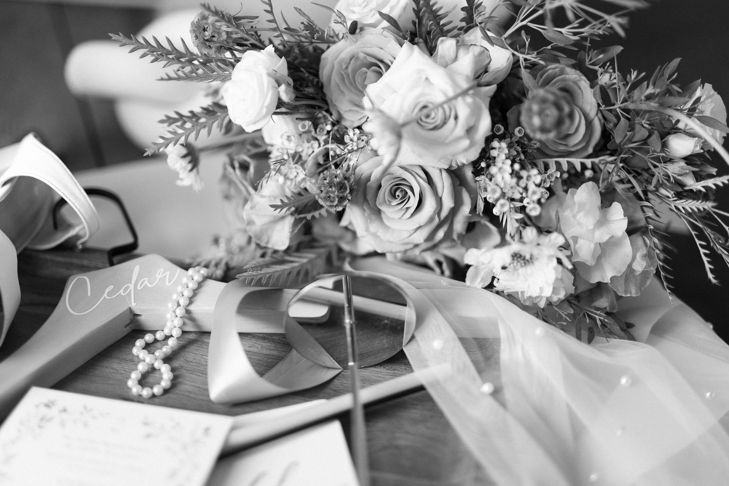 Wedding floral arrangements with white roses and greenery displayed on elegant table settings.
