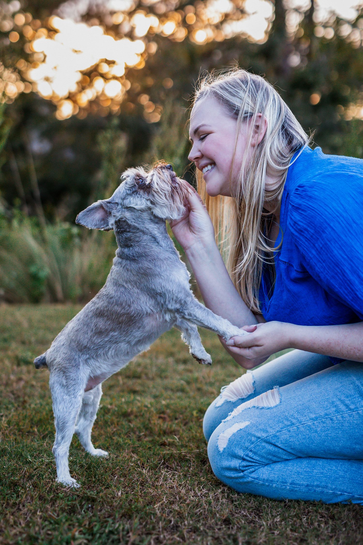 Woman joyfully posing with her dog in a warm, natural setting, taken by local Windsor photographer.