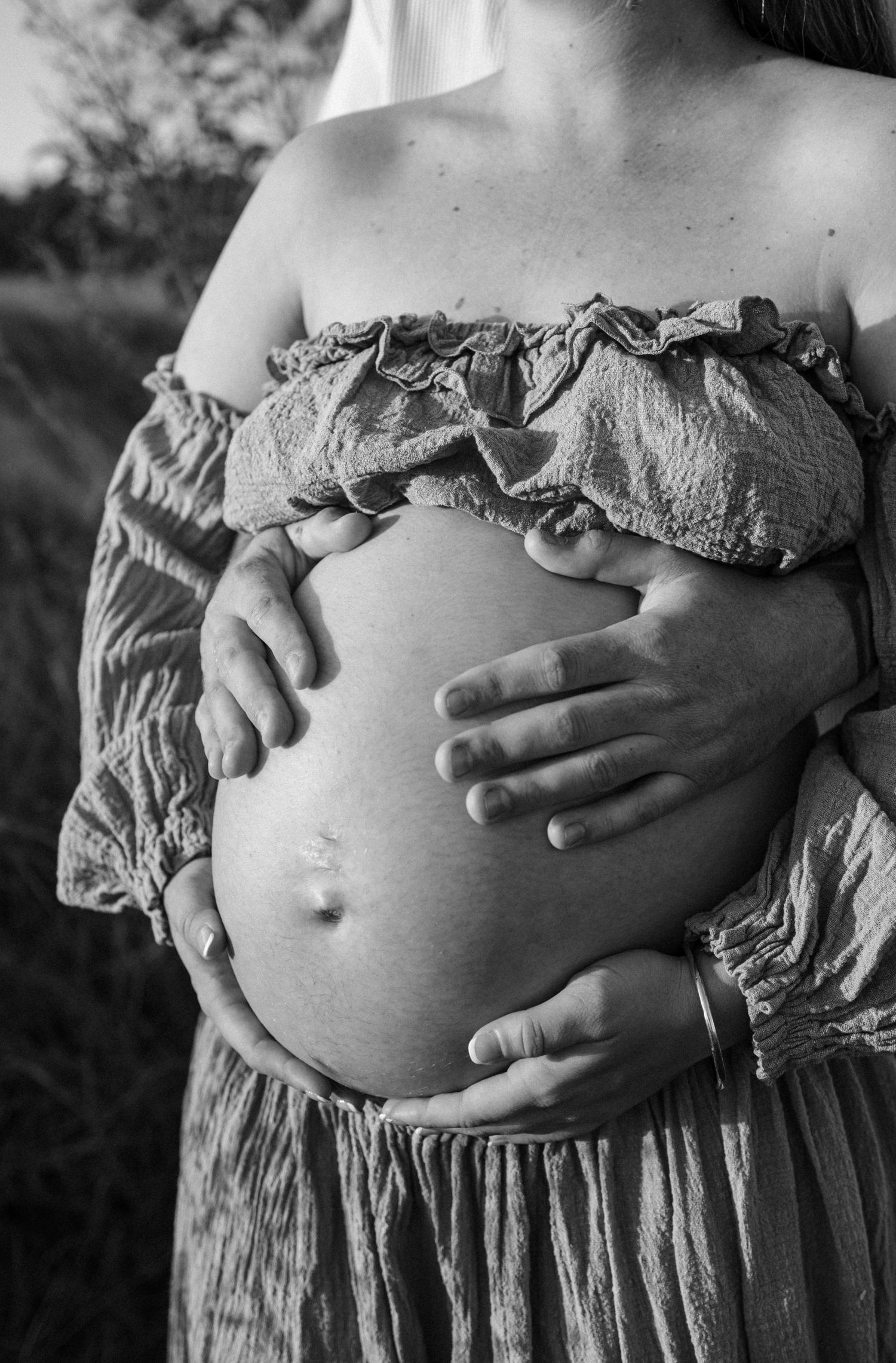A series of black and white photographs showing a pregnant belly with hands gently resting on it in different frames.