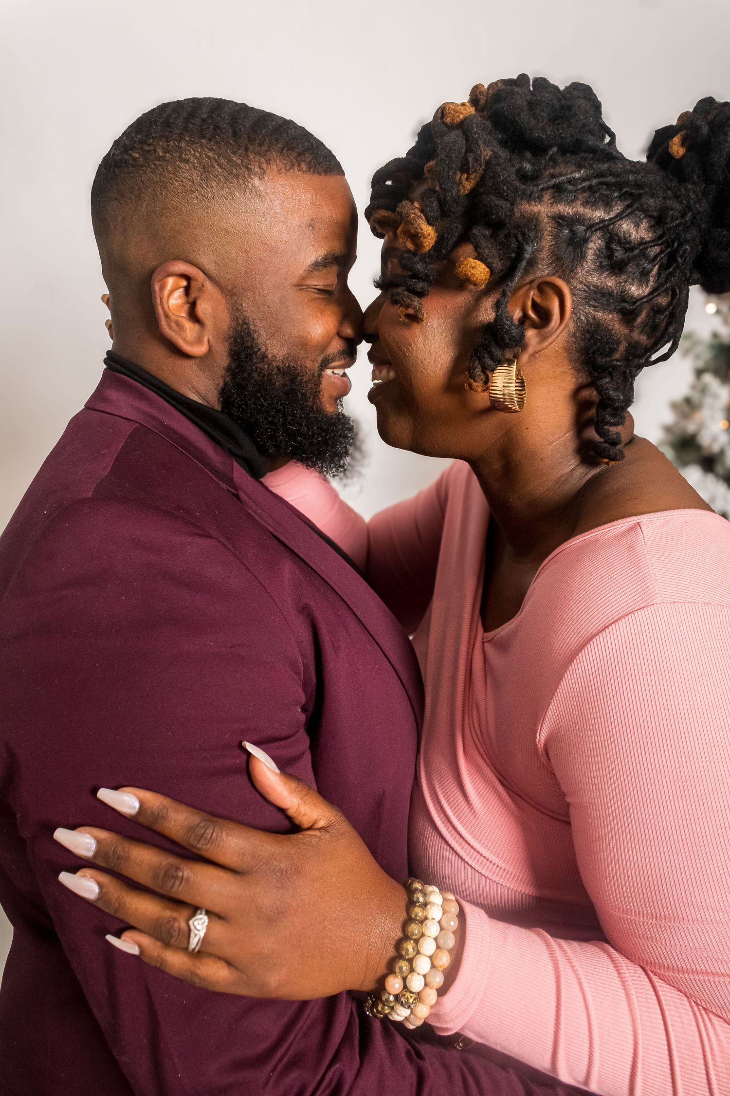 Romantic couple in burgundy and pink embracing during engagement photo session.