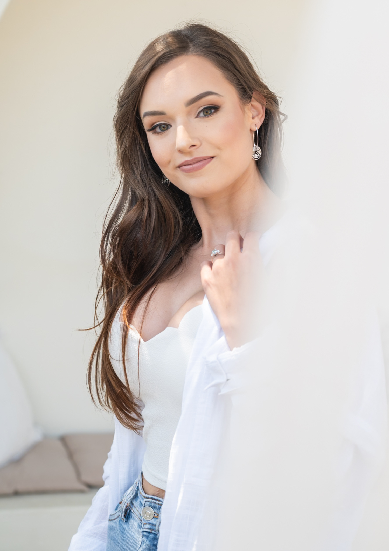 A person in a white button-down shirt poses against a light background in a professional portrait series.