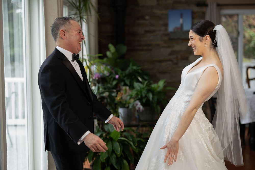 A bride and father share an emotional moment before walking down the aisle at an indoor wedding ceremony.