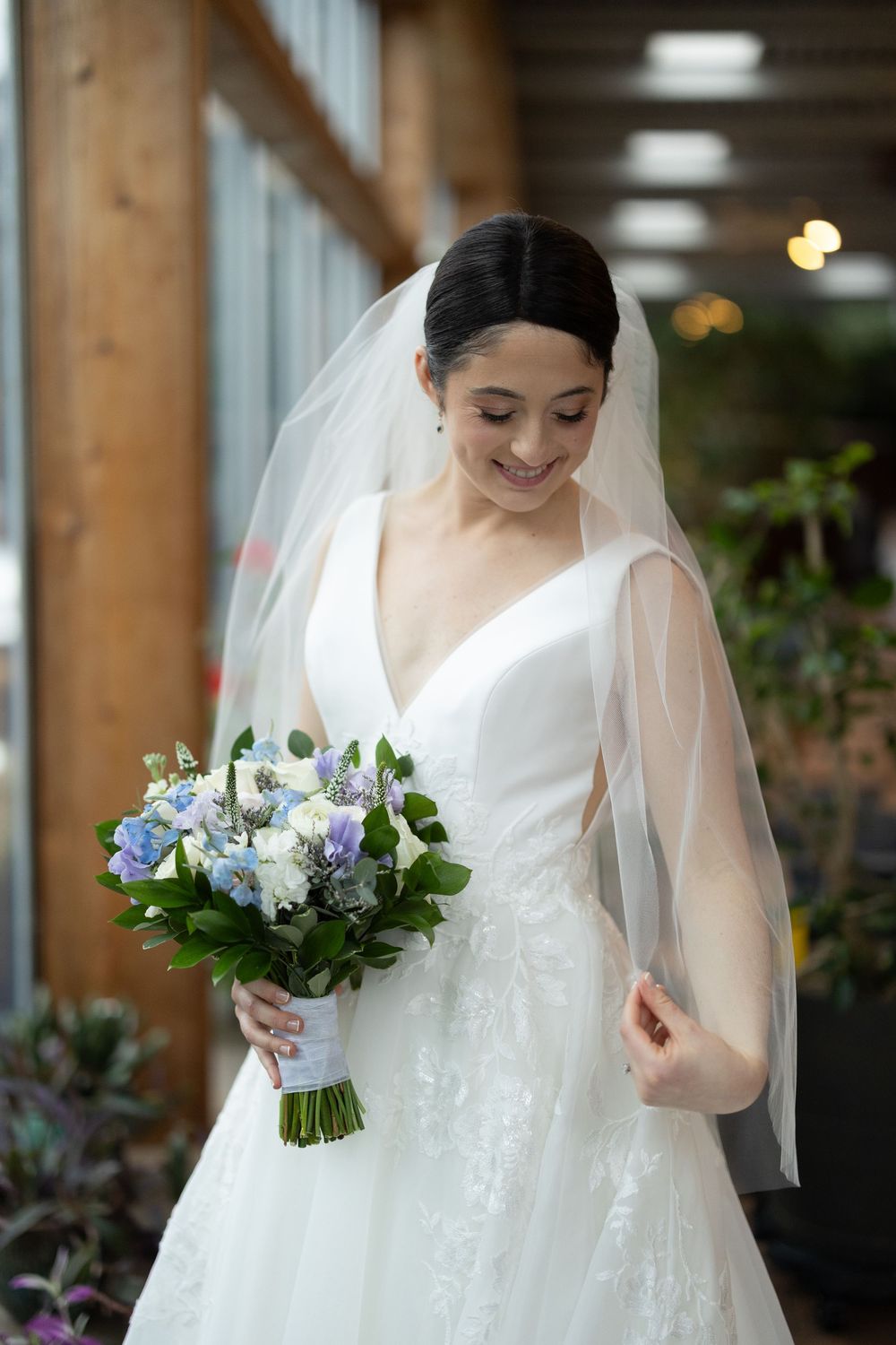 Beautiful bridal portrait showing an elegant white wedding dress and a delicate bouquet of blue and white flowers.