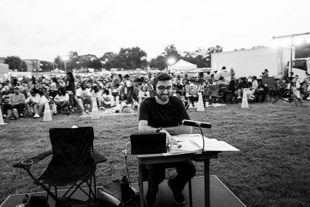People gathered at an outdoor festival with tents and chairs spread across a field.