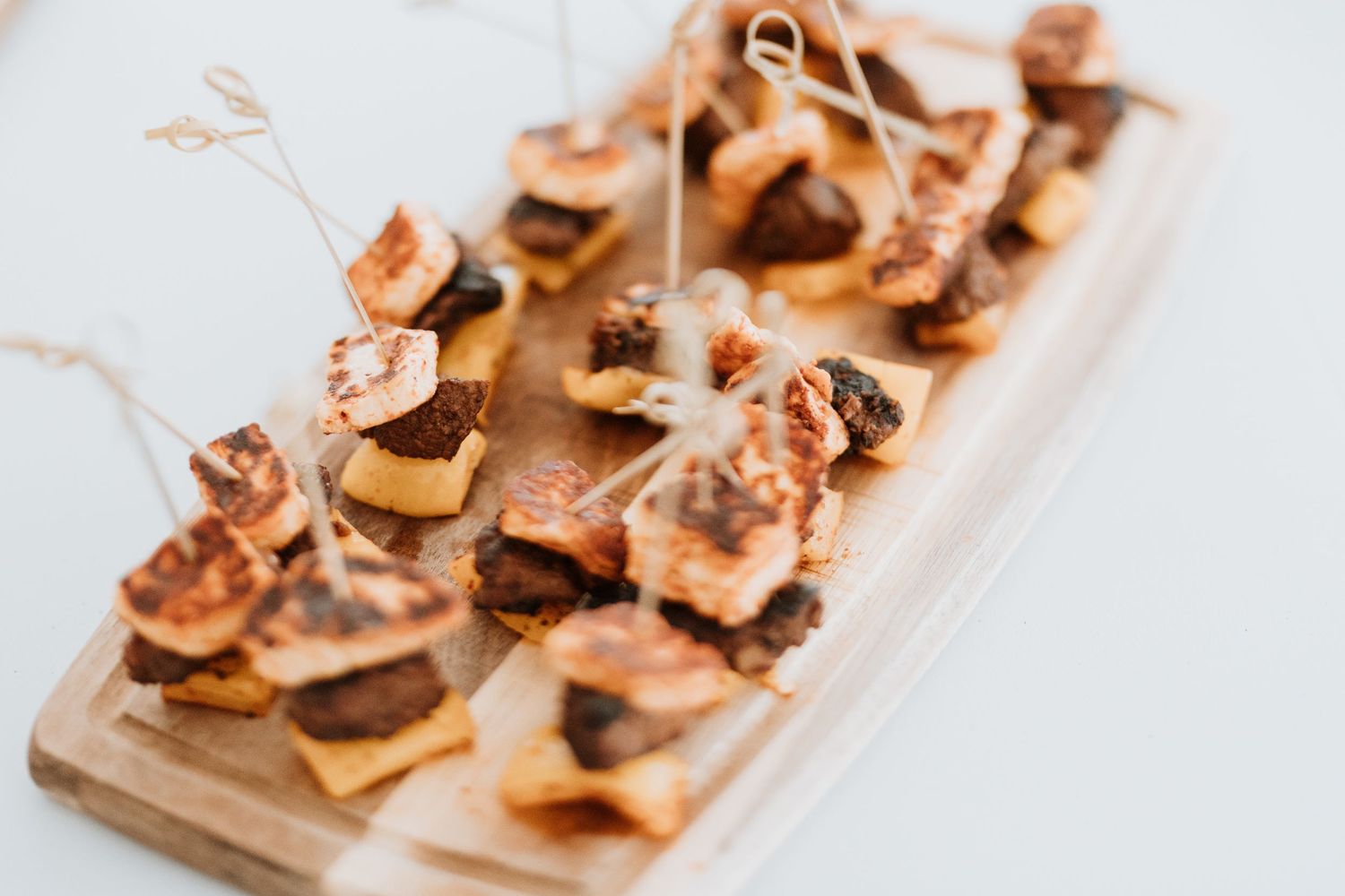 Gourmet appetizers with mushrooms and prosciutto served on a wooden board at an upscale event.