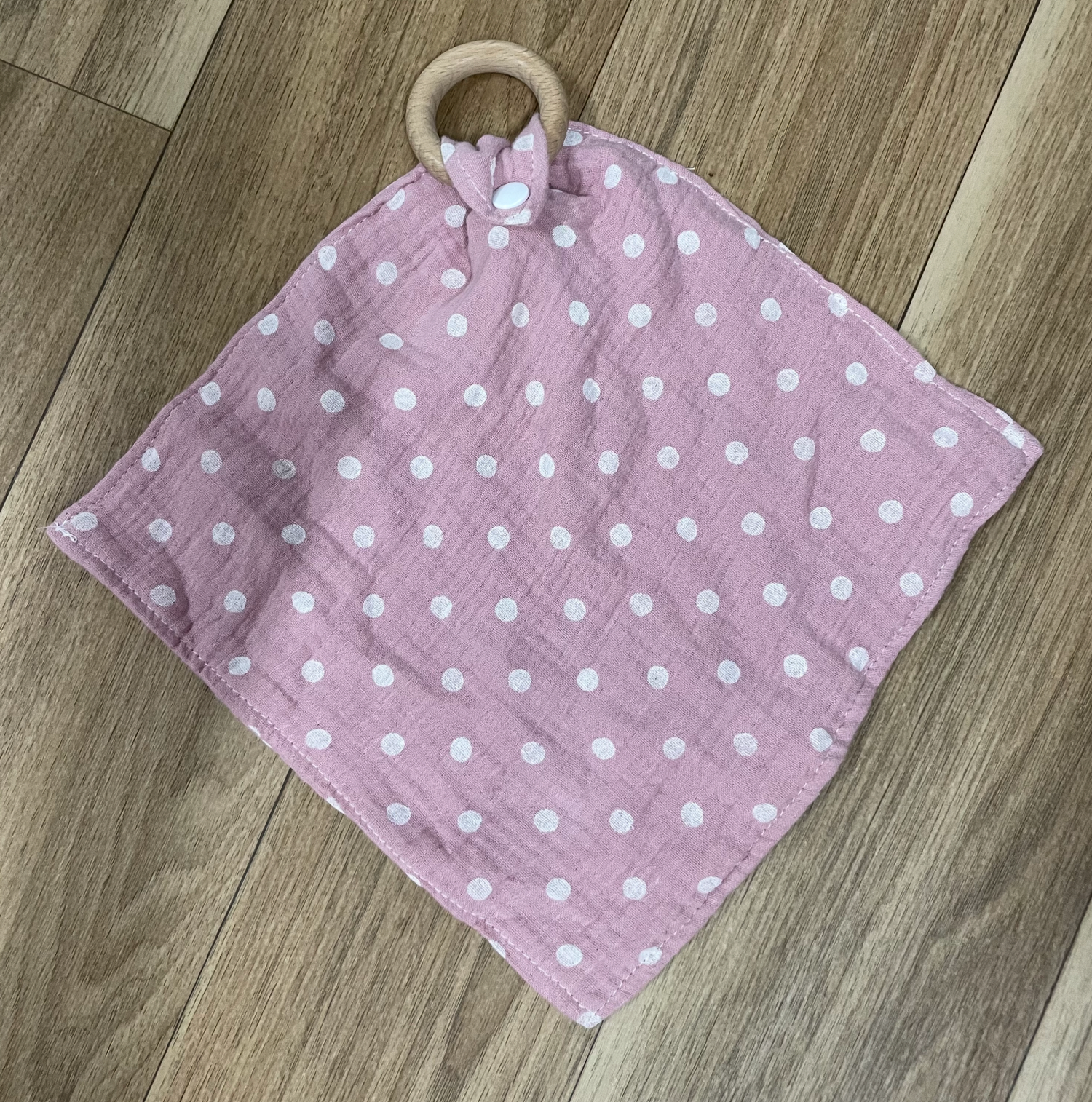 Pink and white polka dot fabric laid out on wooden flooring.