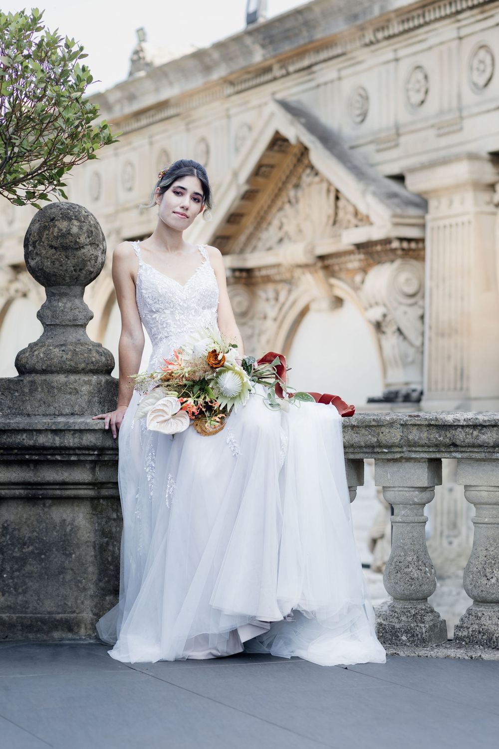 A white bridal gown photographed against classical stone architecture with ornate columns and decorative details.