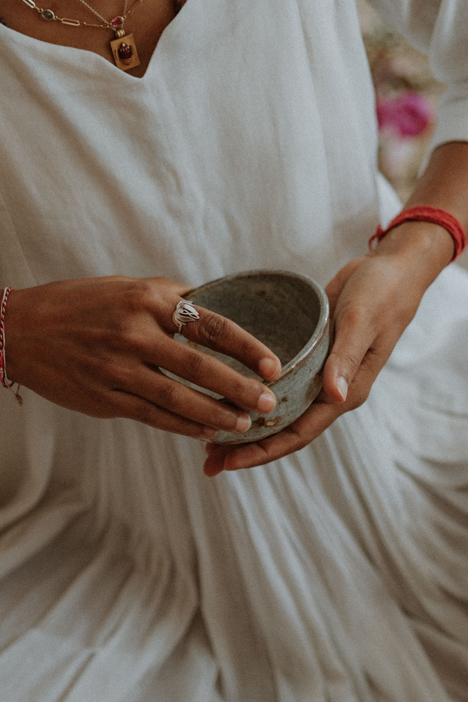 Hands hold a ring in a delicate focused shot with white fabric background creating an intimate detail of a wedding day.