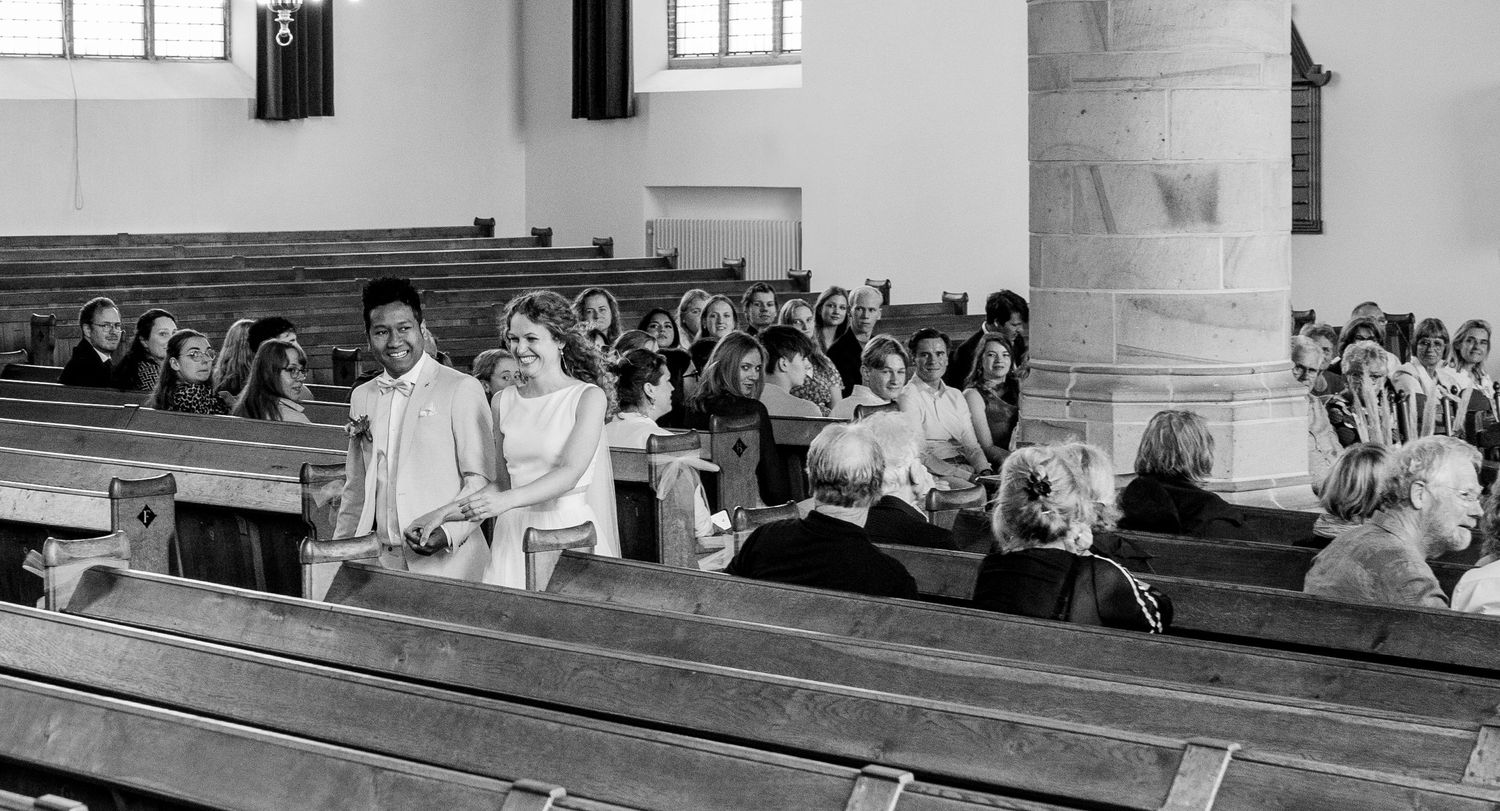 Bruidspaar loopt de kerk in Katwijk uit, en geniet van hun mooie dag.