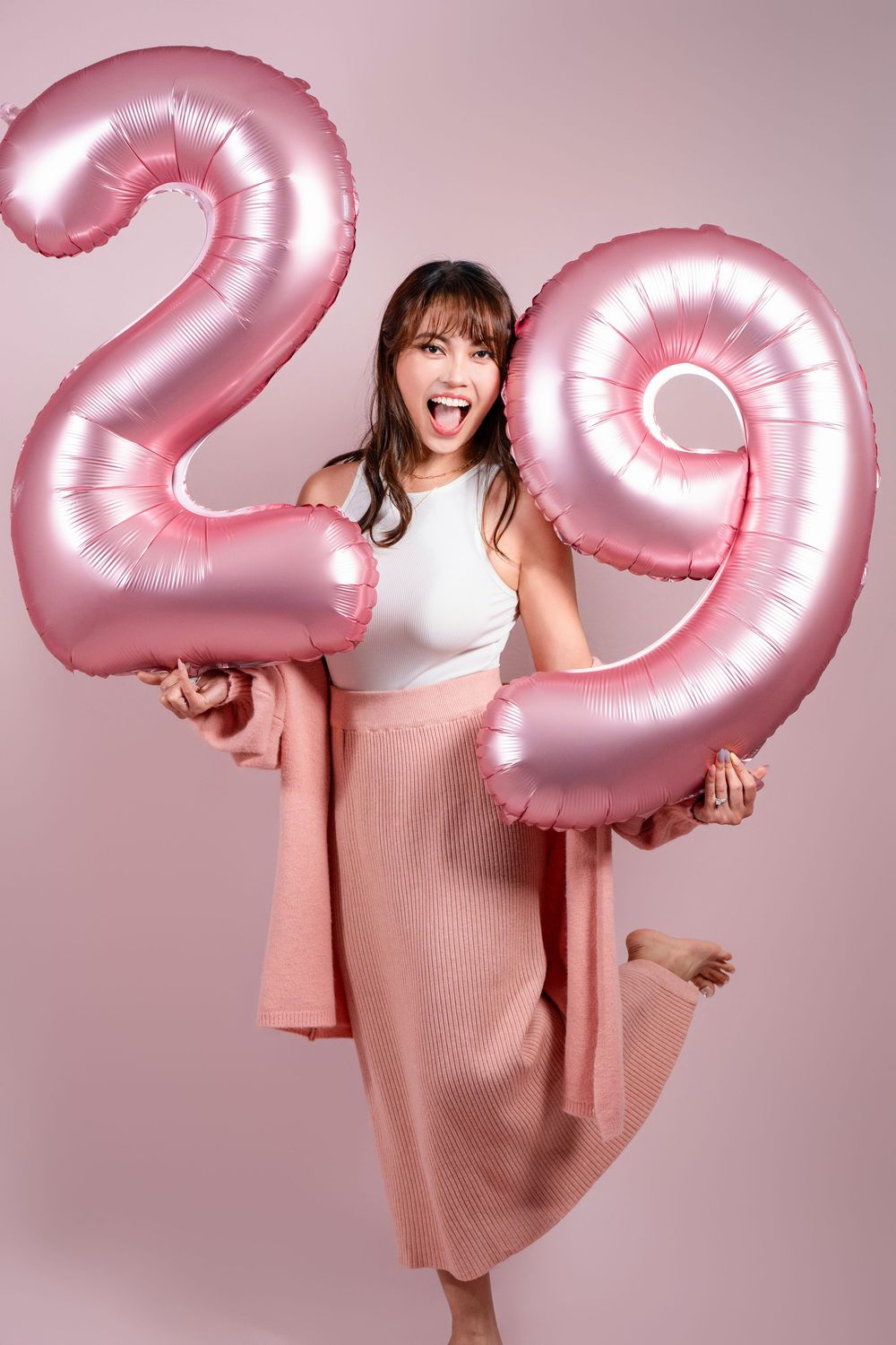 Fun and vibrant indoor 20th birthday studio portrait shot on a pink seamless backdrop by a professional Auckland portrait photographer.