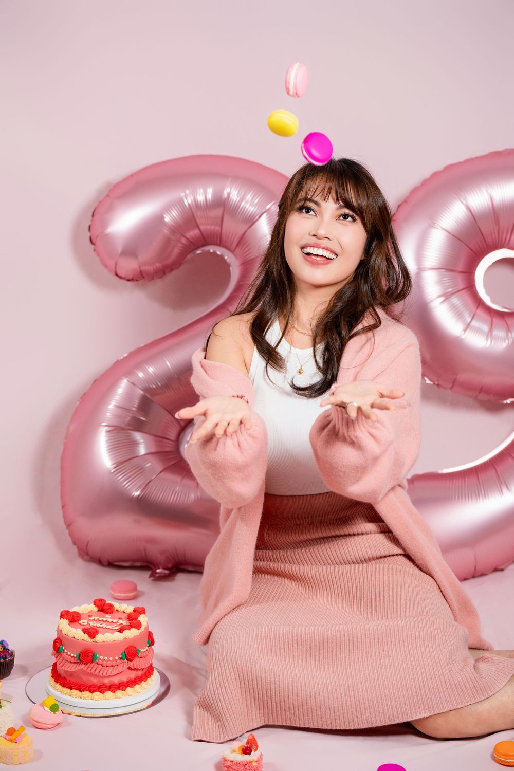 Fun and vibrant indoor 20th birthday studio portrait shot on a pink seamless backdrop by a professional Auckland portrait photographer.