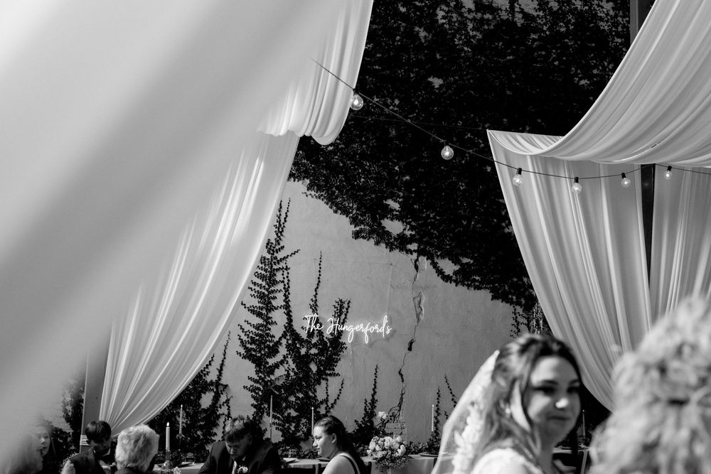 Outdoor wedding reception venue with white drapes and trees creating a romantic evening atmosphere.
