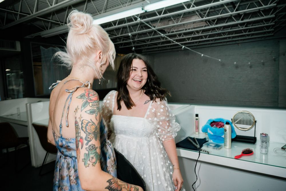 Candid moment between two people getting ready in a backstage area.