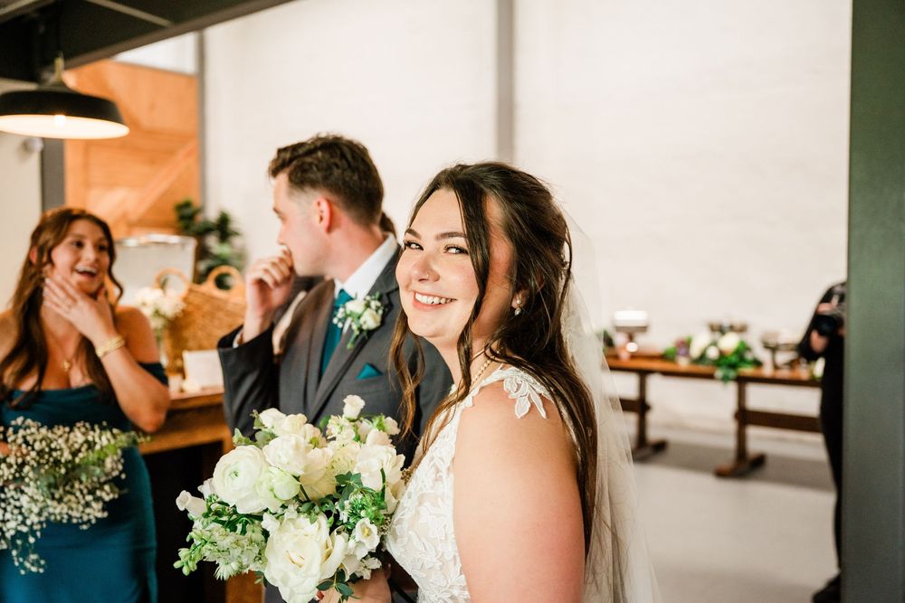 A joyful wedding party celebration with a bride holding a white and green bouquet.
