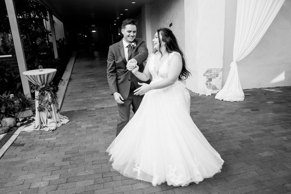 A black and white photo of a newlywed couple dancing together at their wedding reception.