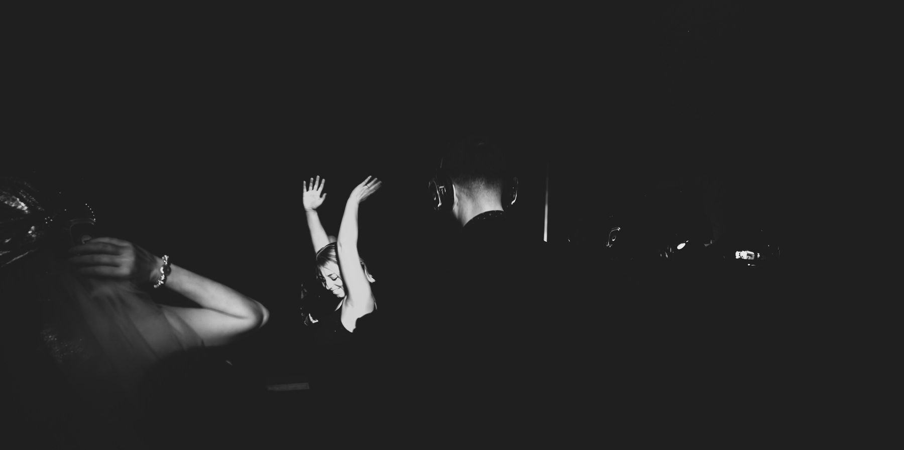 Black and white silhouette of someone leaping through dark space illuminated by dramatic lighting.