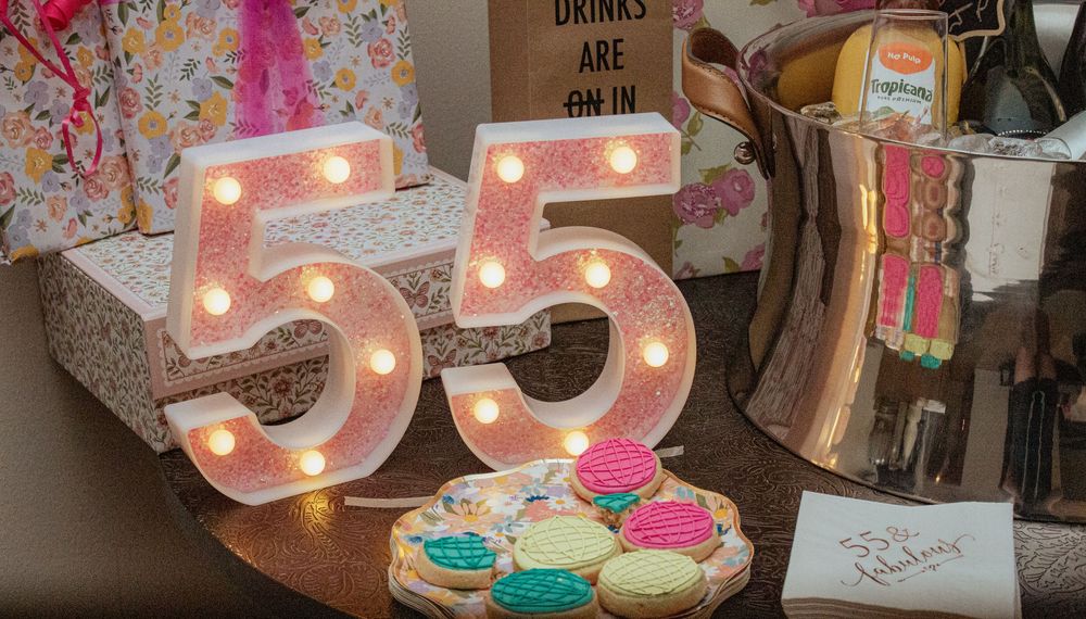 Illuminated number 55 marquee lights with decorative cookies displayed at a celebration party setting.