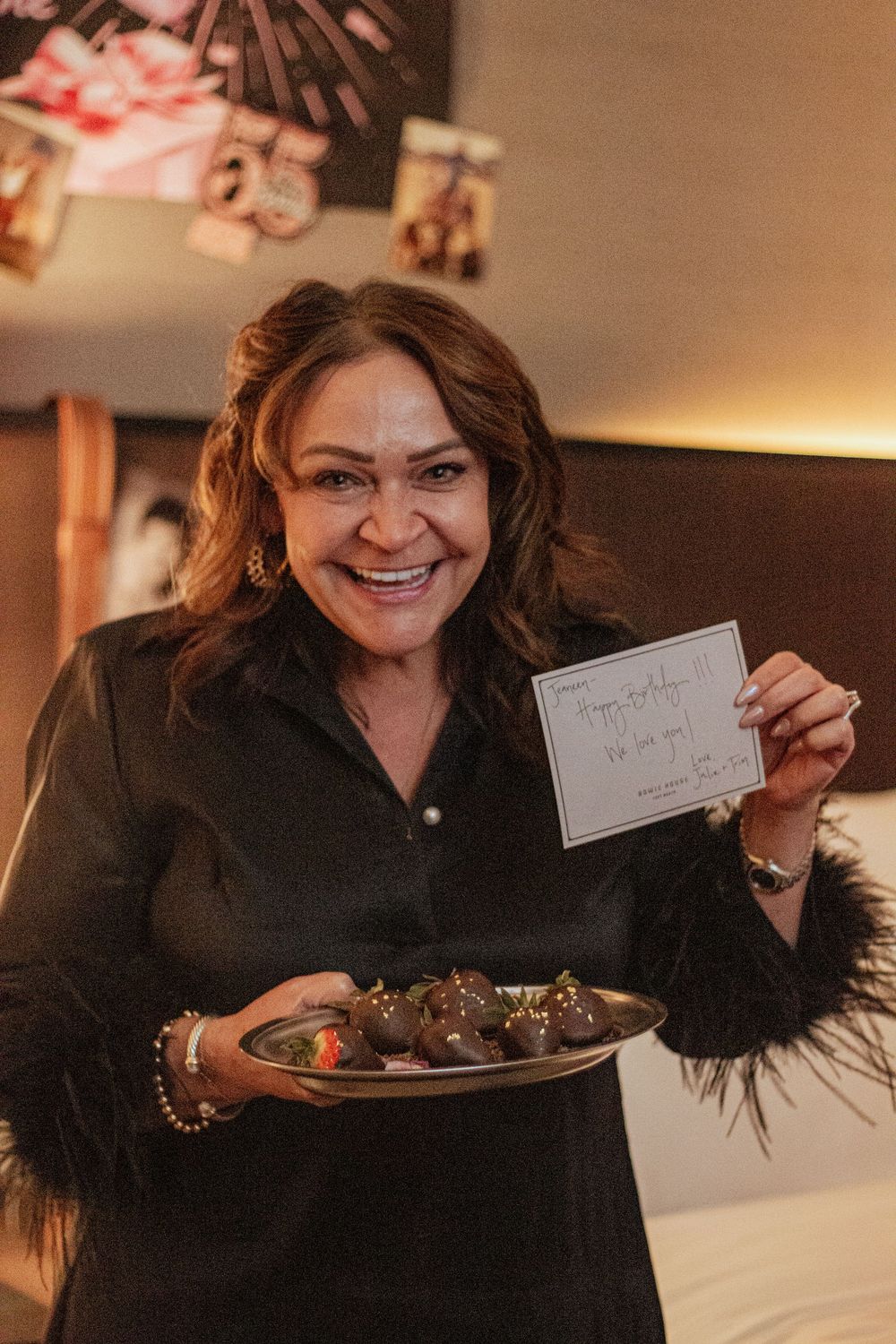 Someone in black clothing shows handwritten thank you notes and presents a plate of chocolate desserts.
