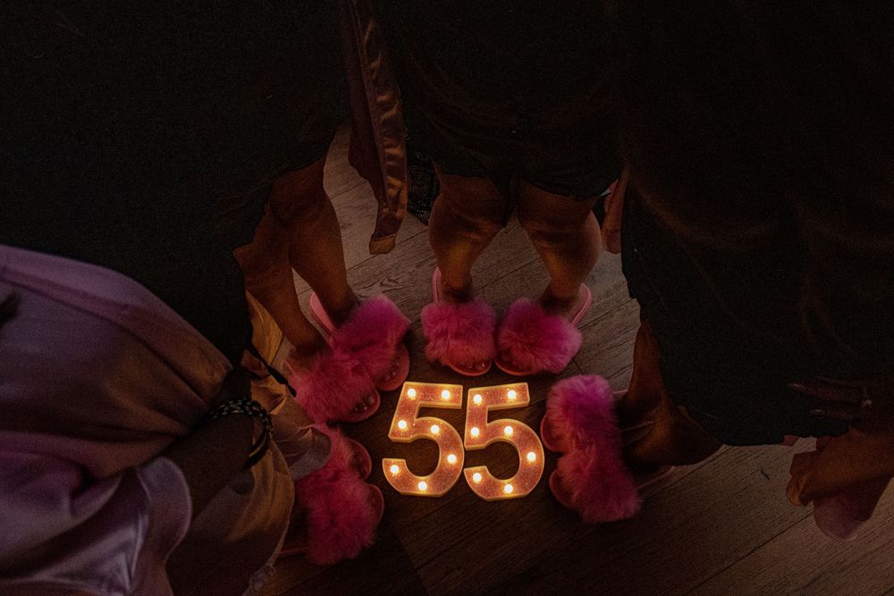 Glowing number 55 sign decorated with red roses and leaves against a dark background.