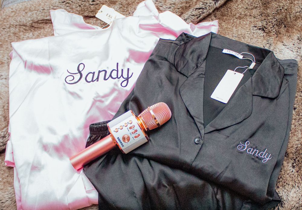 Black and pink embroidered work uniforms with name tags displayed on hangers.
