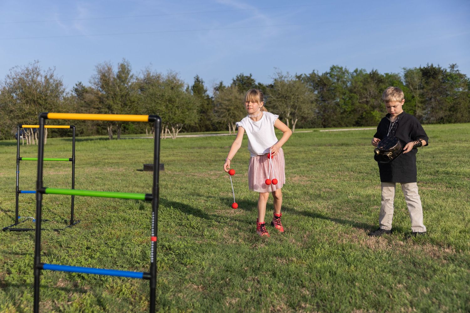 A plastic hurdle obstacle course set up in a grassy field with people practicing jumping drills on a sunny day.