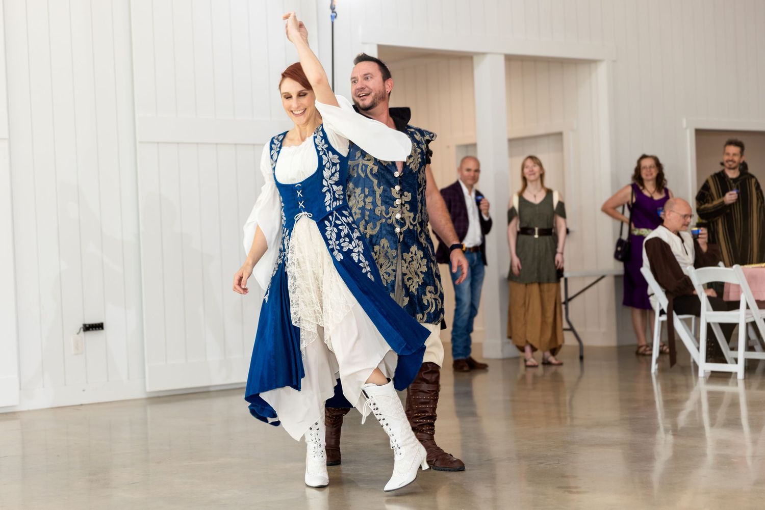 In a bright indoor venue, two dancers perform an elegant routine with one kneeling and the other standing.