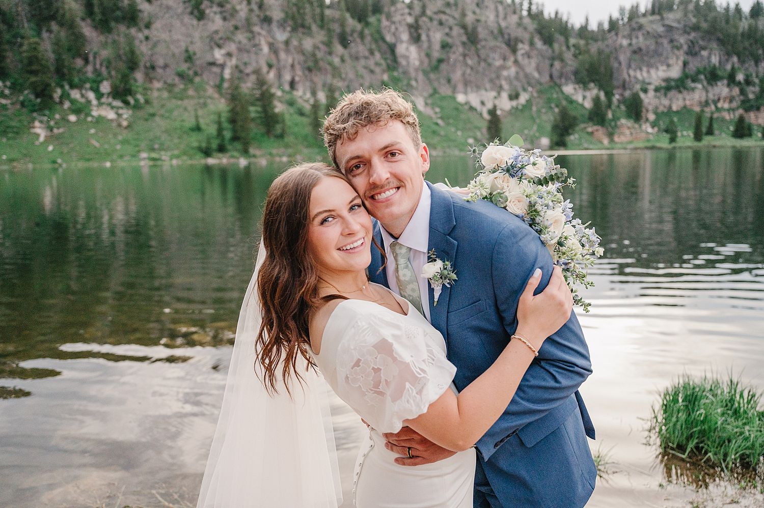 A scenic mountain lake provides a tranquil backdrop for a couple's intimate wilderness wedding photoshoot.