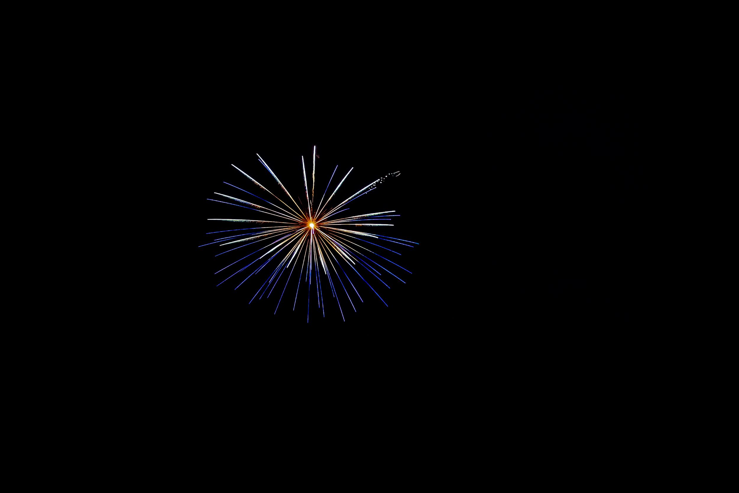 A single blue and orange firework bursts against a dark night sky.