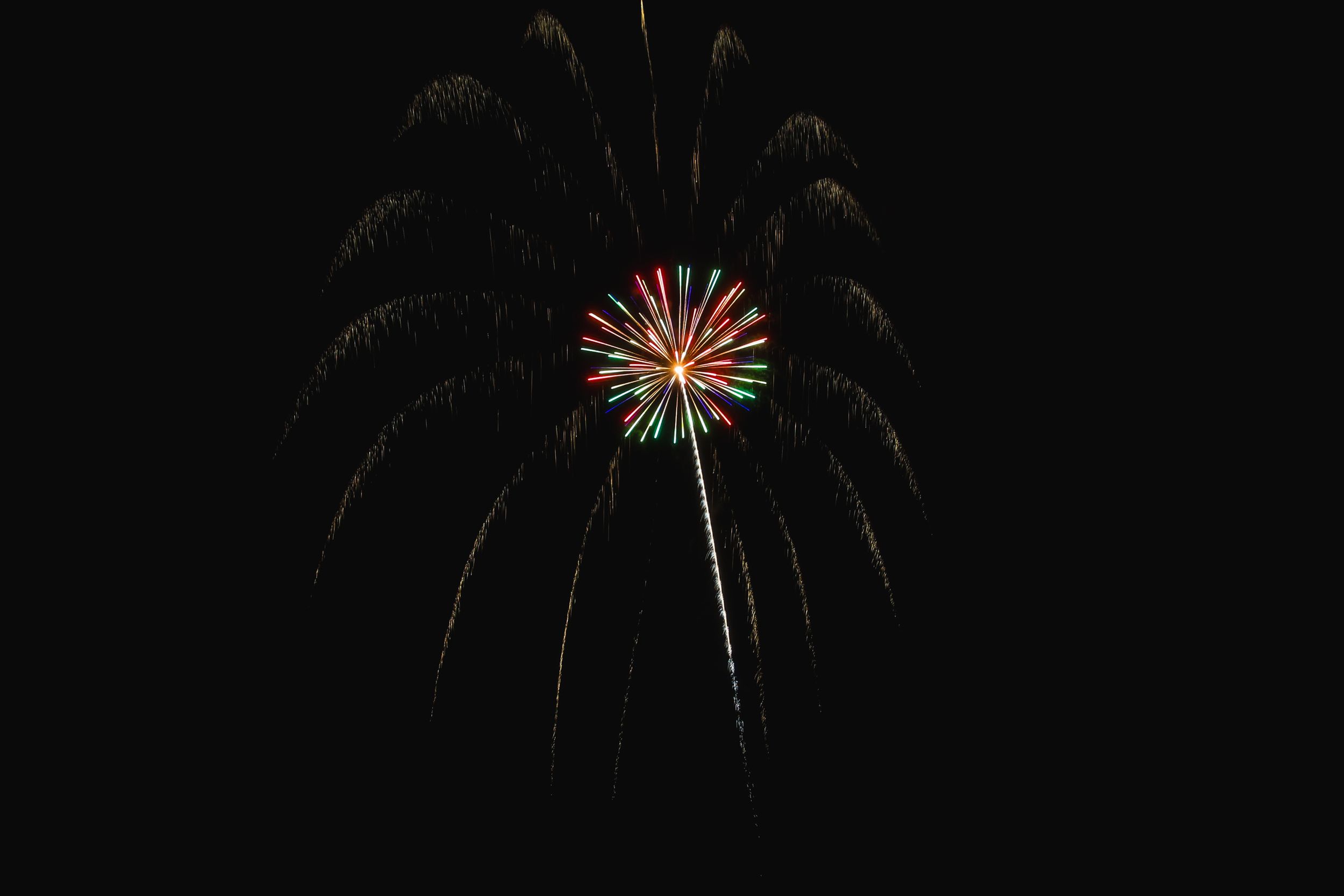 Colorful fireworks burst in sequence against a dark night sky creating a vibrant display of pyrotechnics.