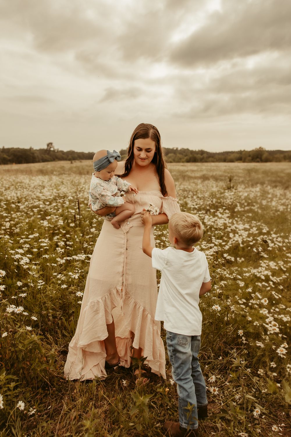 A tender moment captured in a blooming daisy field on a cloudy day as children play in vintage sepia tones. Pine City Minnesota