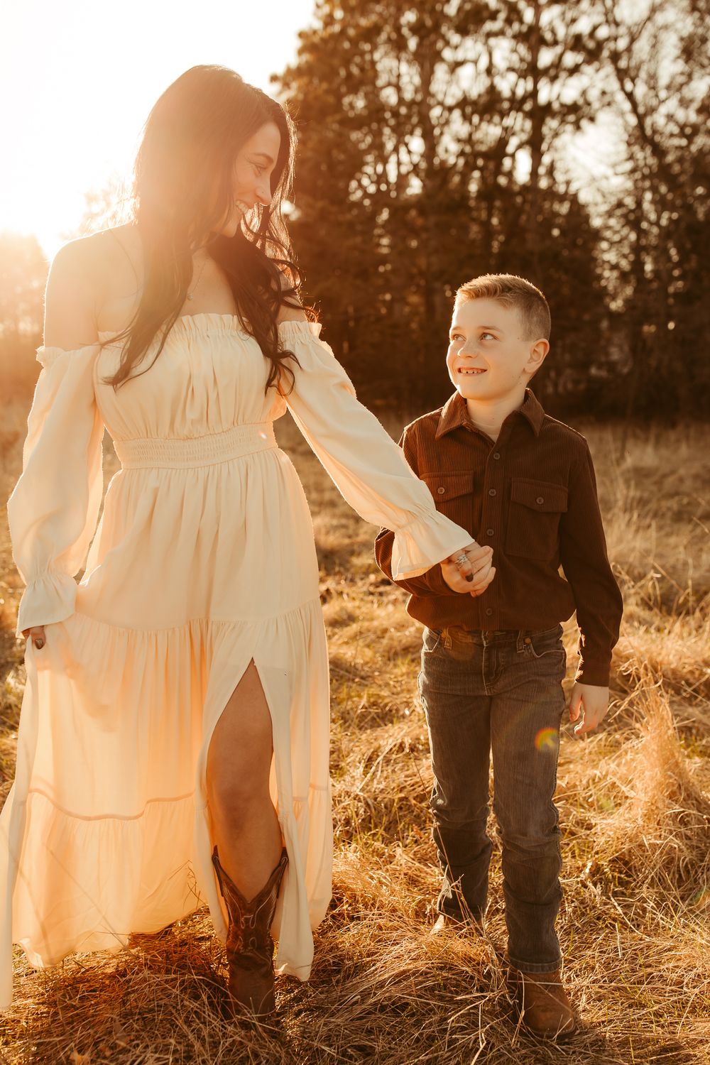 Sun-drenched family photo session in tall grass field during golden hour at sunset with dreamy backlit glow.
