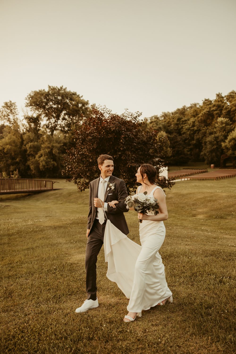 A couple shares an intimate moment on a grassy lawn during golden hour in their wedding attire Cottage Grove Minnesota