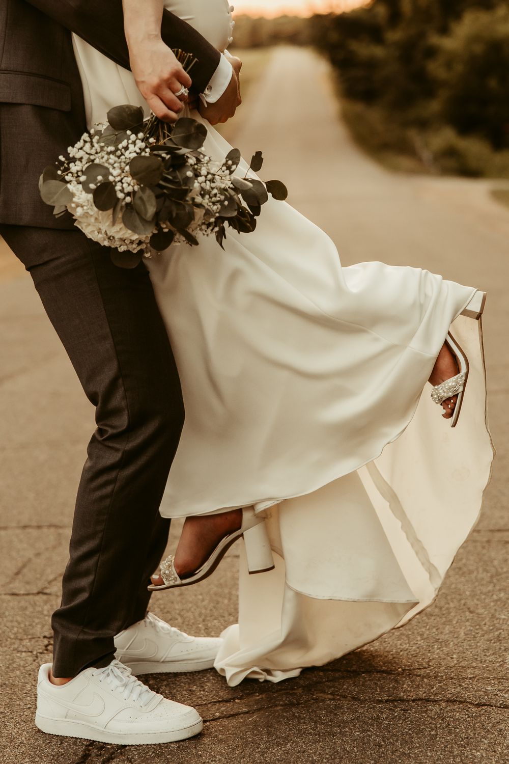 Close-up view of comfortable white sneakers worn with a wedding dress and suit, showing modern casual wedding style.Cottage Grove Minnesota